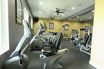 A gym with a variety of equipment including treadmills, stationary bikes, and weight machines.
